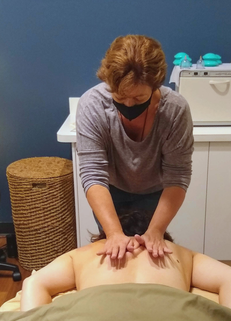 Renu massage therapist with hands on client's back