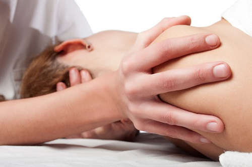 Massage therapist providing massage to shoulder of client